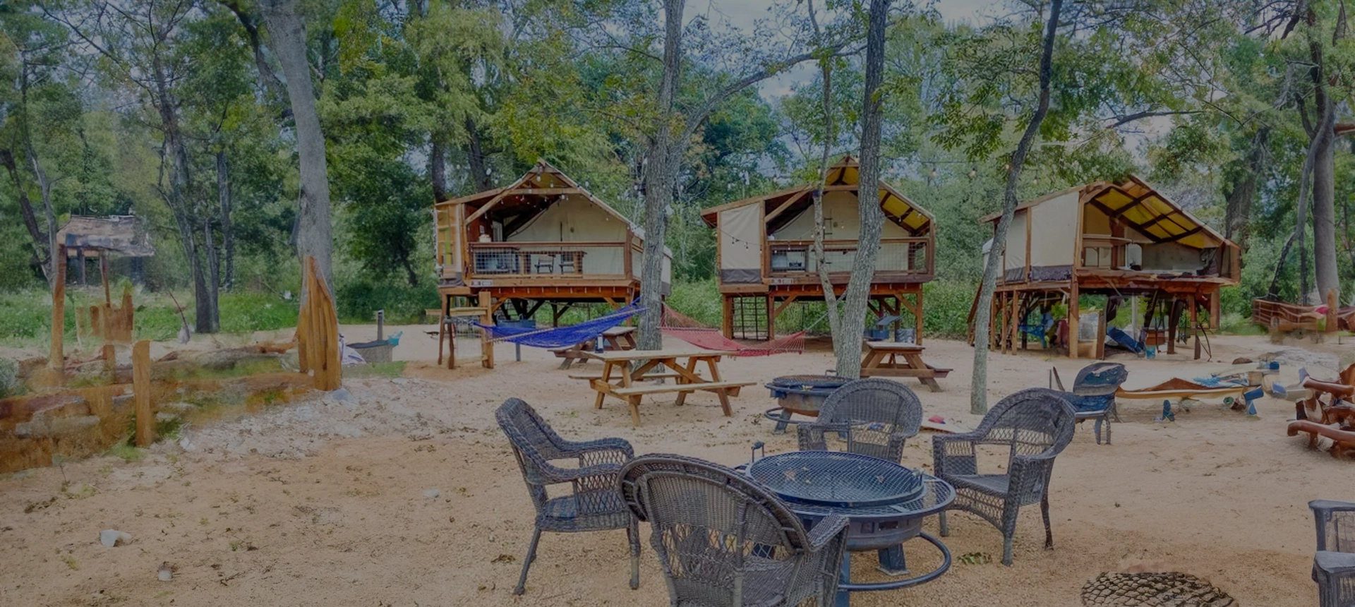 A painting of two cabins and picnic tables