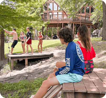 A group of people standing on top of a wooden bench.