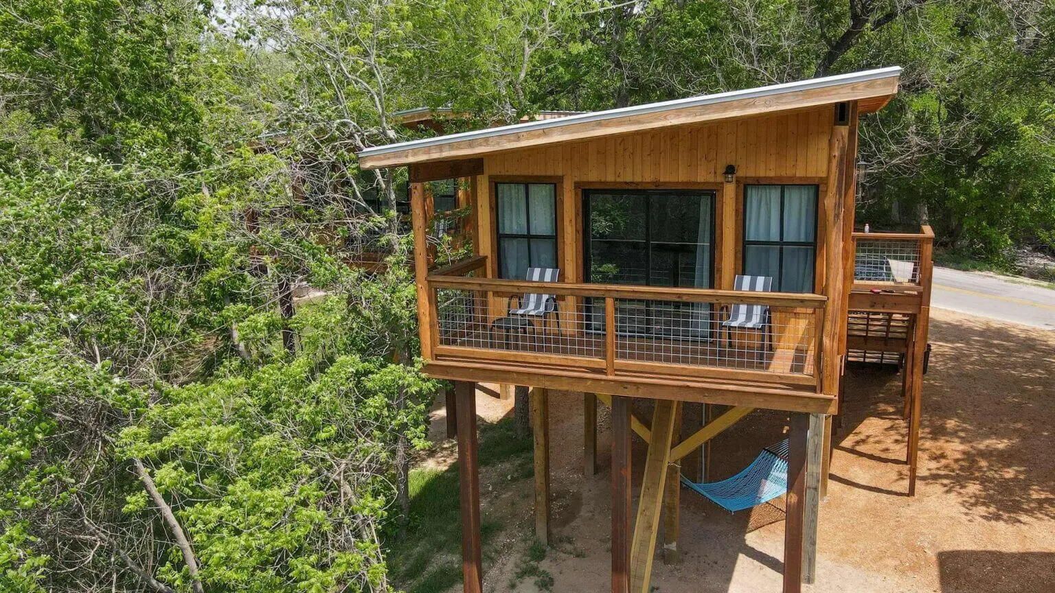 A wooden cabin with a deck and chairs on the side.