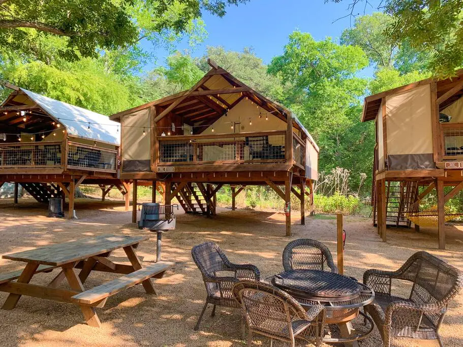 A group of tables and chairs in the middle of a forest.