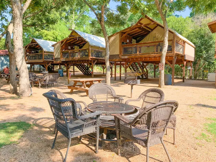 A table and chairs in the sand near some trees