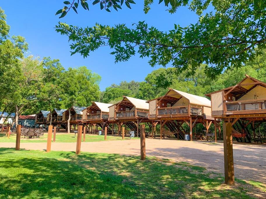 A row of wooden cabins in the middle of a field.