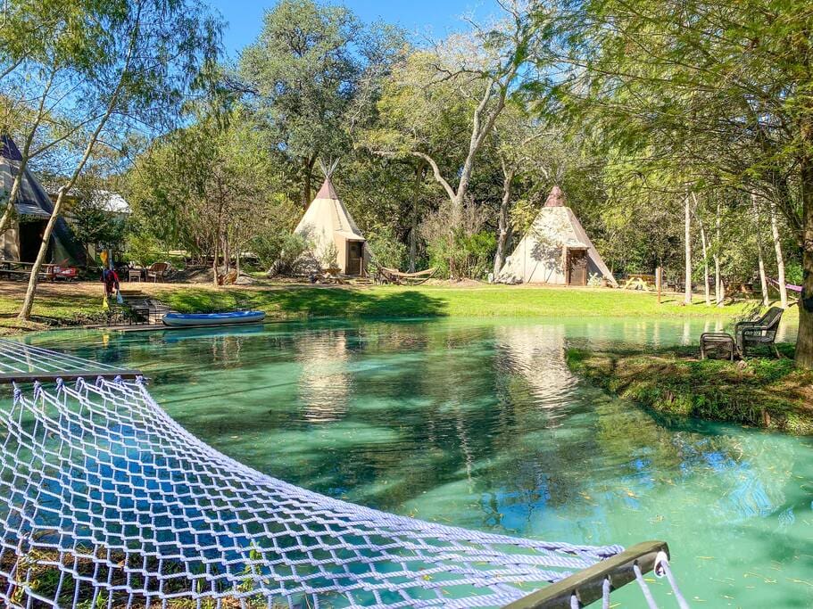 A hammock hanging over the water of a pond.