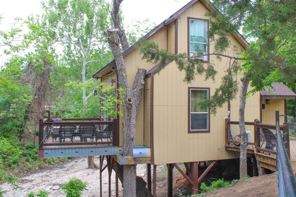 A yellow house with a deck in the middle of it