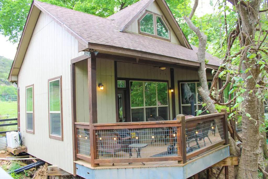 A small house with a deck and a tree